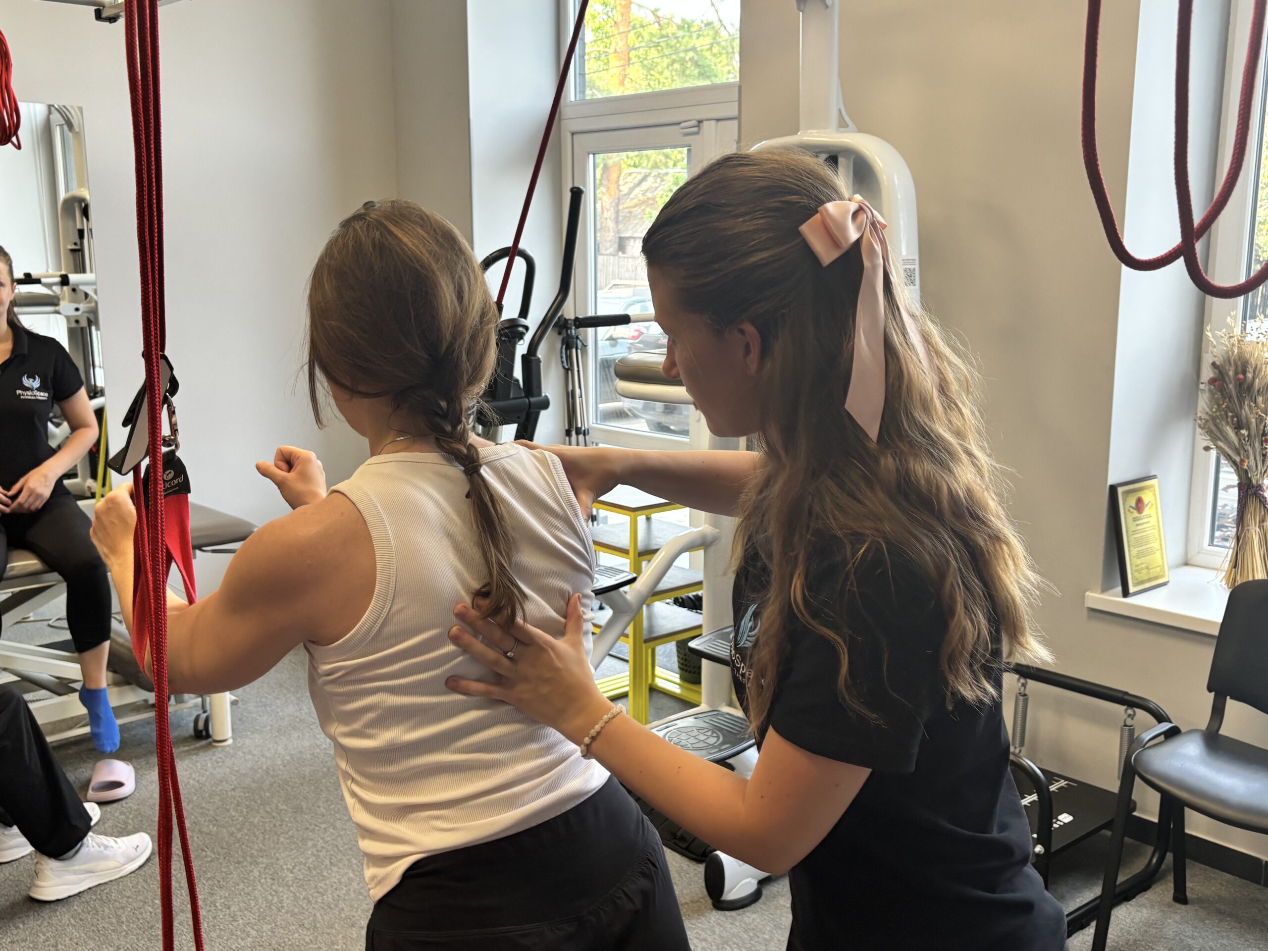 A woman is doing physical therapy under the supervision of another woman, both focused on the exercise